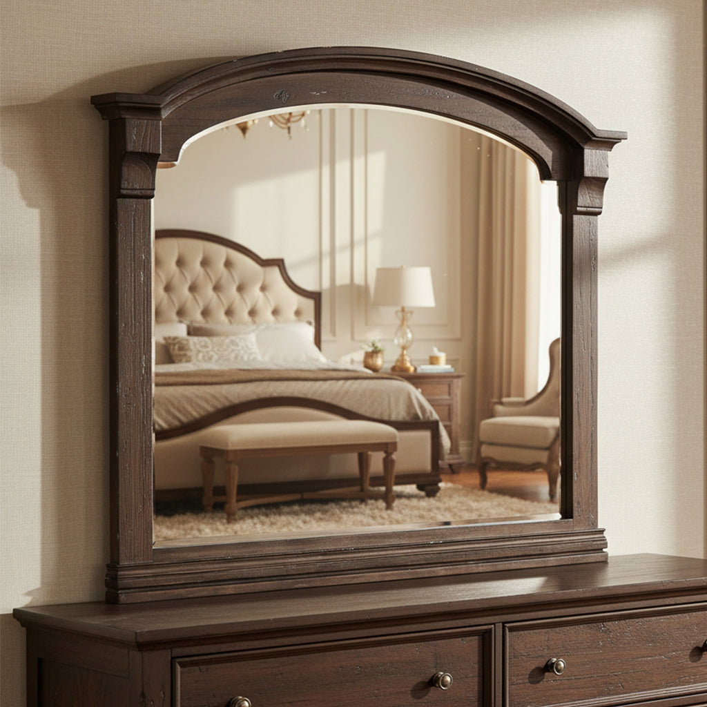 Dark wood Homestead mirror with arched top and beveled glass reflecting cozy bedroom with tufted headboard and nightstand