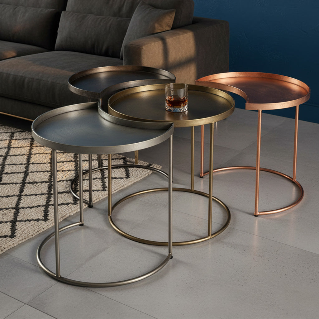 Nesting tables set with three crescent-shaped metal tables in brushed bronze, brass, and copper finishes