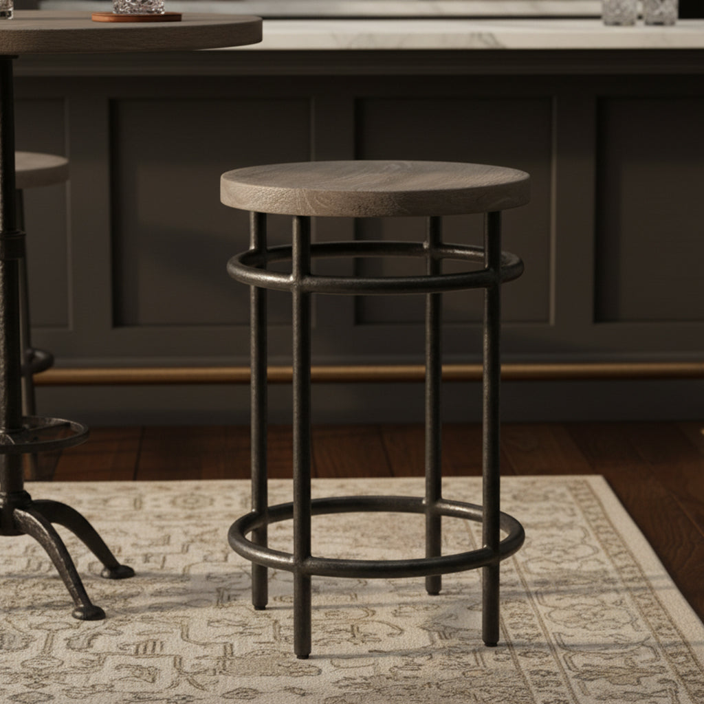 Round Sedona pub stool with solid mango wood top and black iron legs with circular stretchers on patterned rug