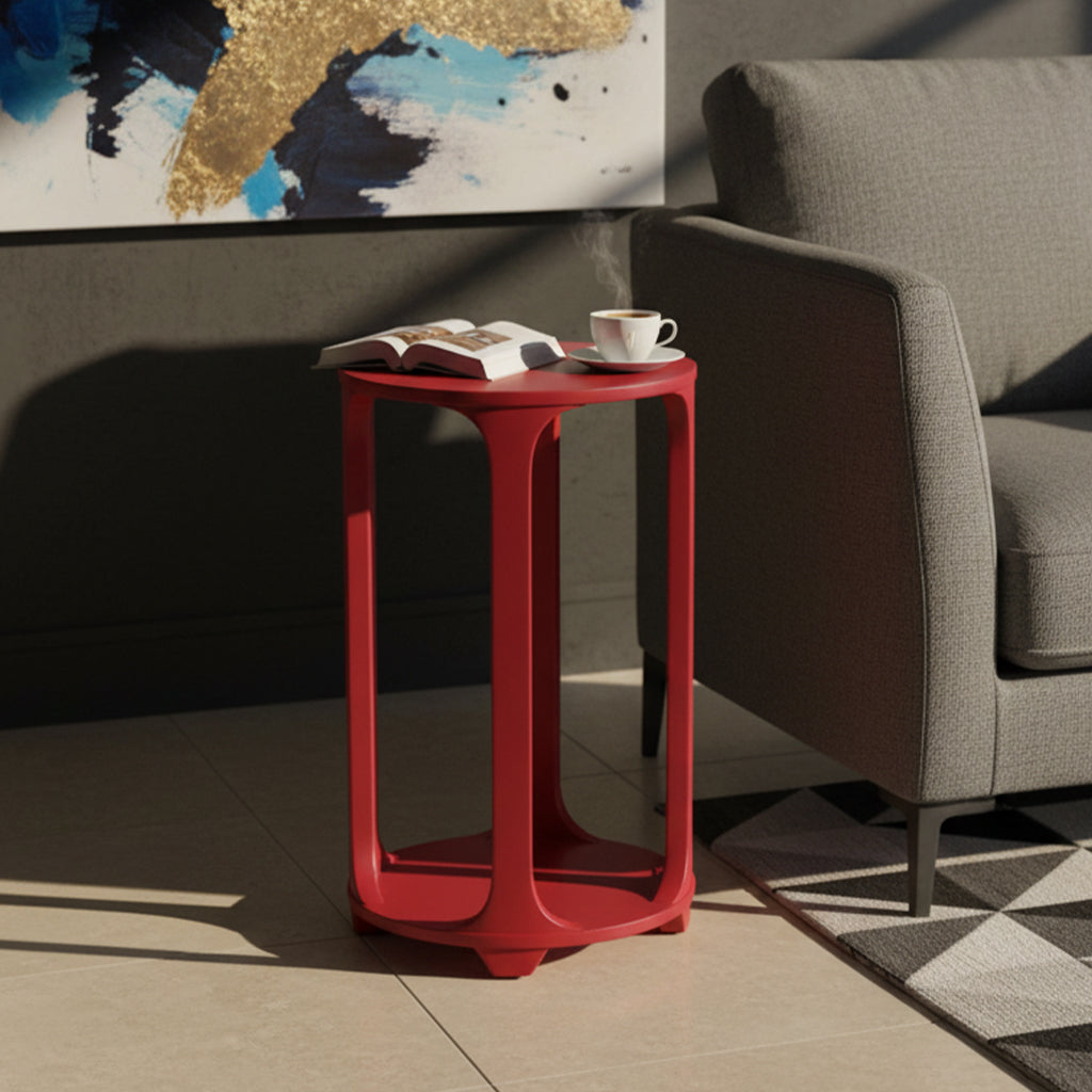 Round pedestal table in red finish with minimalist design, styled with an open book and steaming coffee cup next to gray sofa