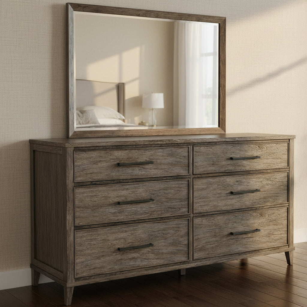 Six-drawer slab top dresser with dark antique brass handles and matching framed mirror in bright bedroom setting